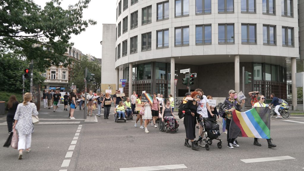 Foto der Laufdemo der Disability und Mad Pride Bonn. Das Foto zeigt die Laufdemo von seitlich vorne. Es sind einige Teilnehmer*innen zu sehen.